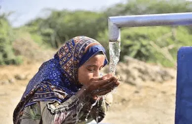 Children gathering around water containers