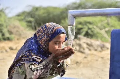Children gathering around water containers
